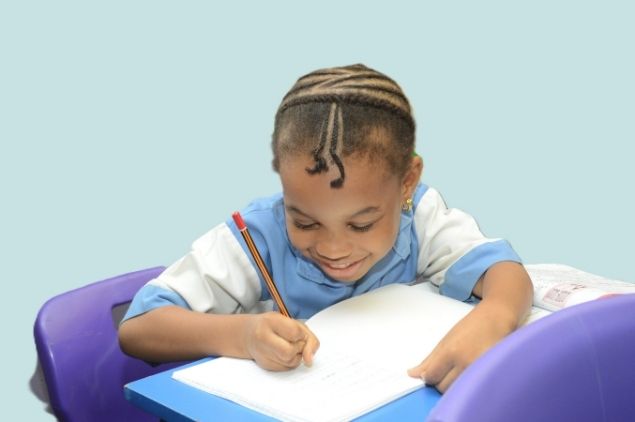 A Dandave School pupil writing carefully in his notebook